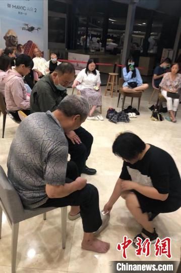 图为凌晨，郑州市一商场工作人员为受困老人买新拖鞋。　李贵刚 摄