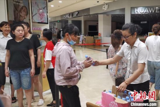 图为凌晨，郑州市一商场工作人员为受困人员提供饮用水。