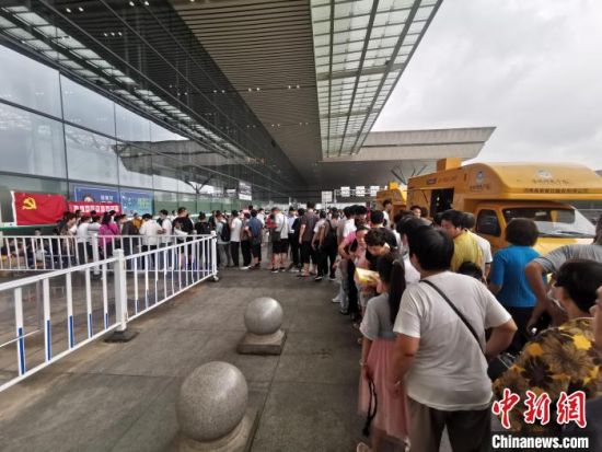 郑州东站三楼进站口外，滞留旅客正在排队取餐。　李明明 摄