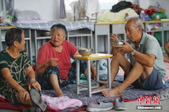 7月23日，设置于河南省安阳市安阳县高庄镇第四中学的暴雨灾害集中安置点内，村民在吃早餐。该安置点共安置附近9个村庄1300多人。 中新社记者 张畅 摄