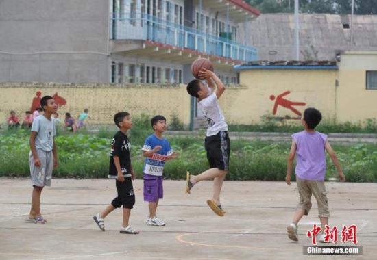 　7月23日，设置于河南省安阳市安阳县高庄镇第四中学的暴雨灾害集中安置点内，小朋友在打篮球。中新社记者 张畅 摄