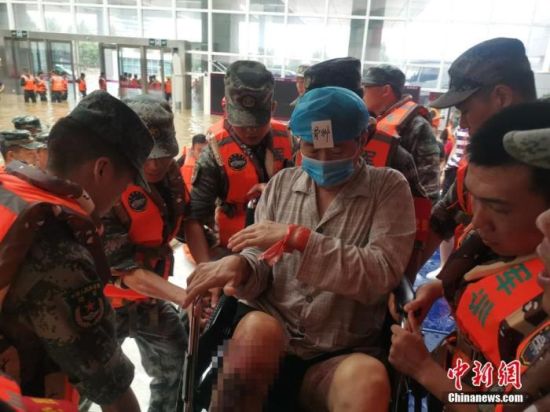7月22日，受灾严重的郑州市阜外华中心血管病医院向外转运患者。图为救援人员转移一名骨伤患者。 中新社发 李明明 摄