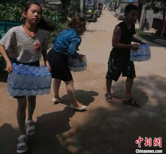 儿童没被要求撤离之前，一名女童跟着大人为护堤人员送水。　付清顺 摄