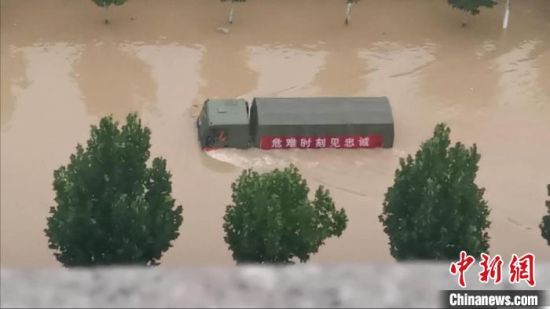 图为7月21日郑州东部地区被洪水围困，一辆军车在洪水中破浪前行。　张佳琪 摄