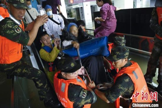 　图为火箭军某部官兵转移被洪水围困的病人。　陈世锋 摄