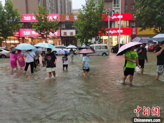 　资料图：郑州7・20特大暴雨后，市民在街道上趟水而过。　王登峰 　摄