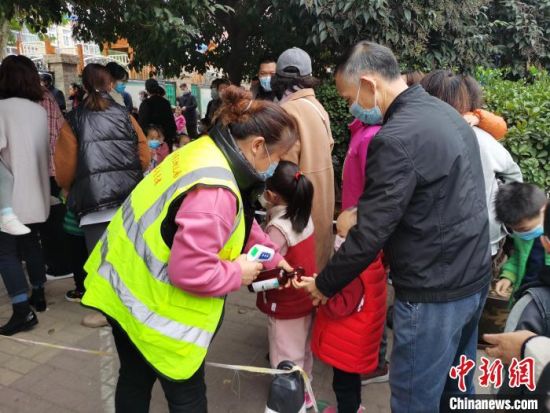 图为郑州金水区三幼校工作人员为孩子测量体温、喷洒消毒液。　王登峰 摄