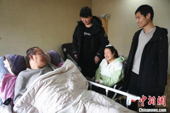 　残友基地创始人王绍军(左一)躺在病床上与学员交流工作、生活情况。　韩章云 摄