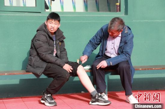 图为教练为裴福鑫的受伤部位擦拭药水。　阚力 摄