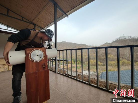 图为王耀斌演示自制的反射望远镜。　阚力 摄