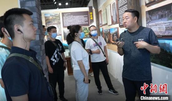 刘志平在向游客讲解毛铺村发展史。王宇 摄