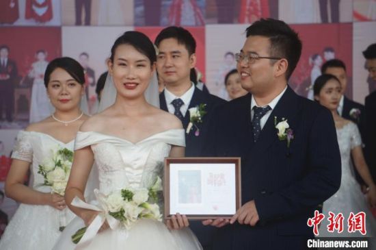 参加集体婚礼的新人收到婚礼纪念照片。韩章云 摄