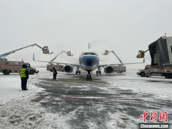 图为郑州机场工作人员给飞机除雪。郑州机场 供图